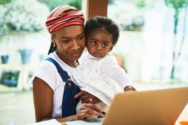 woman-holding-baby-looking-at-laptop